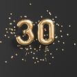 Zahlen-Luftballons in gold, die 30 ergeben. Darum herum Konfetti.
