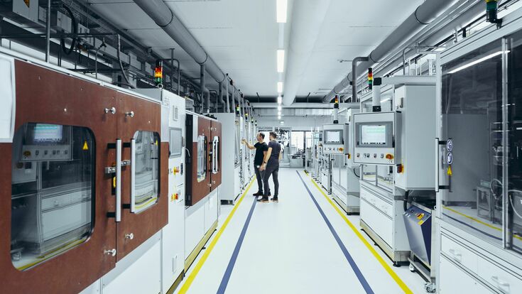 © Hansgrohe SE Ein Blick in das Labor: Zwischen den Reihen an Maschinen stehen zwei Männer.