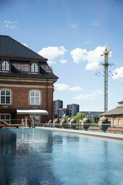 © AXOR / Hansgrohe SE Der Pool vor der in roten Backsteinen gehaltenen Villa, im Hintergrund sieht man den Kettenprater des Tivoli.