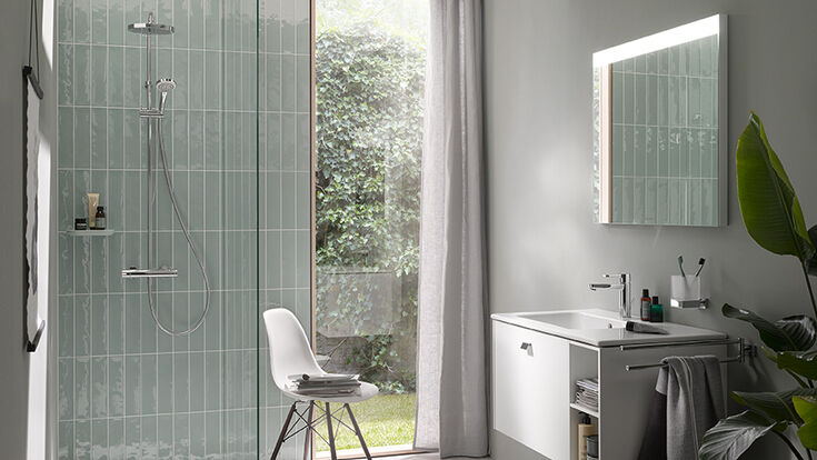 © Duravit Ein in minzgrün gehaltenes Badezimmer mit bodenebener Dusche und einem Waschtisch mit Spiegel darüber.