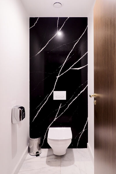 © Melia Hotels International Blick frontal zur weißen Keramiktoilette vor einer schwarzen Marmorwand.