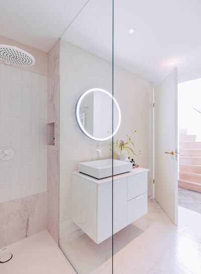 © Eines der Badezimmer im Obergeschoss des „Townhouse“ ist ins Schlafzimmer integriert. Das Kinderbadezimmer mit einem weißen Waschtsich und beleuchtetem Badezimmerspiegel.