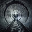 Diggers are exploring underground river flowing in round sewer tunnel
