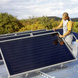 Flachdach-Solarkollektoren und ein Mann, der daran arbeitet.
