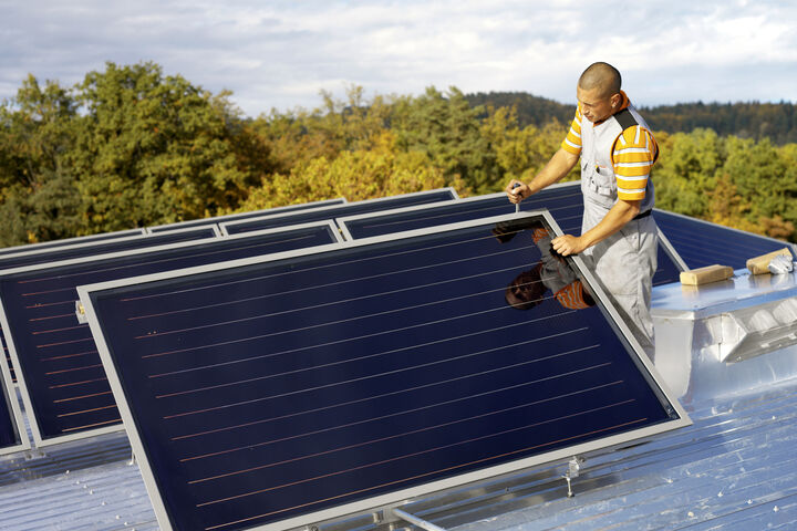 Flachdach-Solarkollektoren und ein Mann, der daran arbeitet.