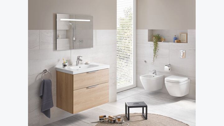 Einzelwaschtisch mit Unterschrank, WC und Bidet in einem kleinen, hellen Badezimmer.