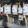 Electricity and electrical maintenance service, Engineer hand holding AC multimeter checking electric current voltage at circuit breaker terminal and cable wiring main power distribution board.