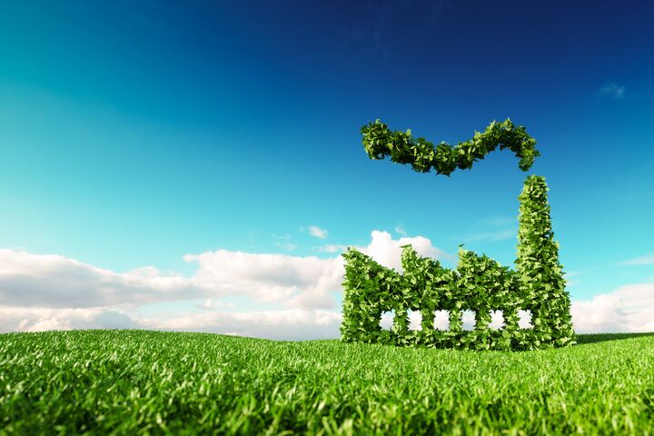 Eco friendly industry concept. 3d rendering of green factory icon on fresh spring meadow with blue sky in background.