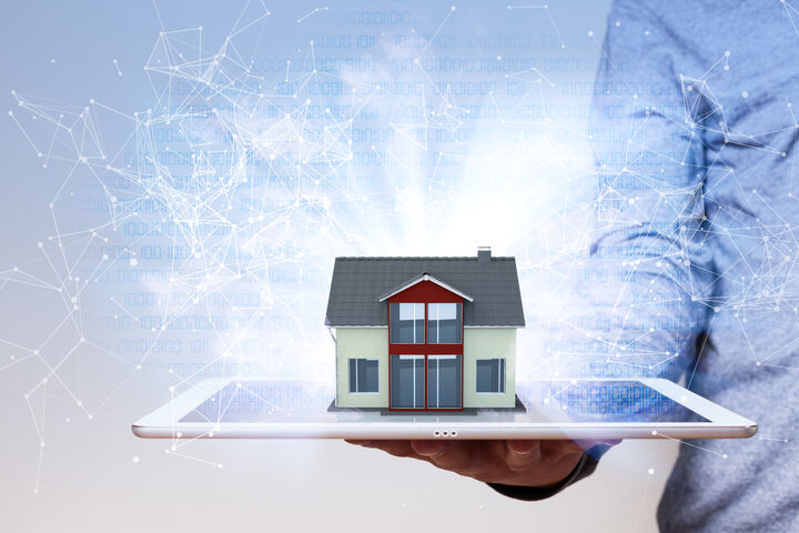 Hand hält ein Tablet, aus dem das 3D-Rendering eines Hauses aufsteigt.