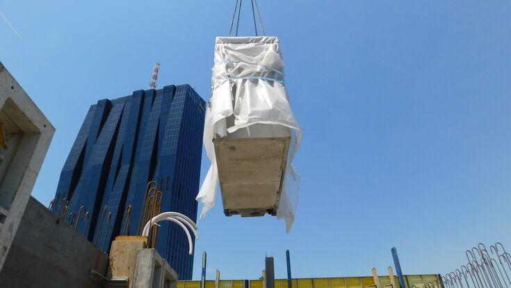 © S&B Gruppe Die vorgefertigten Beton- Fertigteilbäder werden vor em Hintergrund des DC-Towers 1 per Kran an den richtigen Platz gebracht.