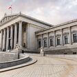 main entrance of Austrian parliament building in Greek style with statues of philosophers and white columns with famous Pallas Athena fountain and in Vienna