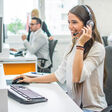 Young smiling operator woman agent with headsets working in a call center.
