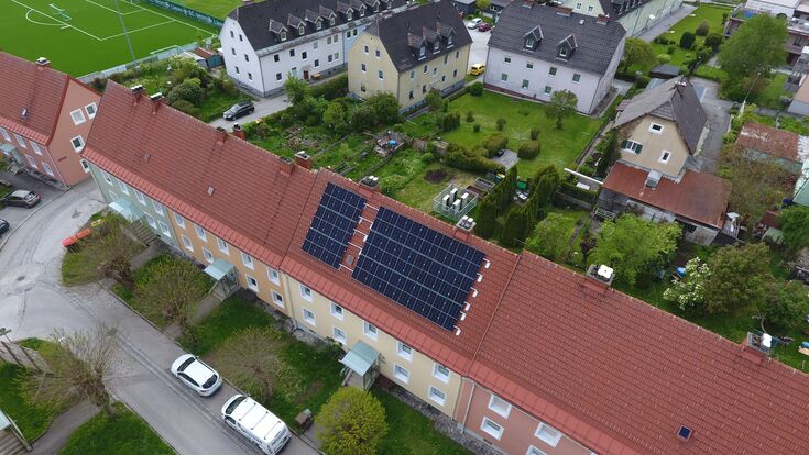 Das HAPPENING-System kommt in einem zusammenhängenden Riegel aus fünf Gebäuden in Liezen zum Einsatz. Heizzentrale und Photovoltaik-Anlage sind im beziehungsweise auf dem mittleren Gebäude installiert. Klein in Weiß hinter dem Gebäude zu erkennen sind die Außeneinheiten der Luftwärmepumpen.