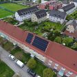 Das HAPPENING-System kommt in einem zusammenhängenden Riegel aus fünf Gebäuden in Liezen zum Einsatz. Heizzentrale und Photovoltaik-Anlage sind im beziehungsweise auf dem mittleren Gebäude installiert. Klein in Weiß hinter dem Gebäude zu erkennen sind die Außeneinheiten der Luftwärmepumpen.