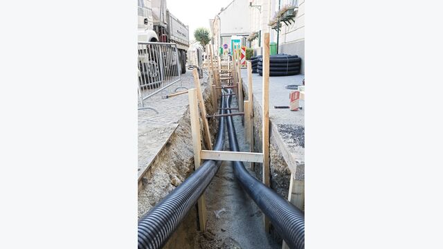 Installation von vorisolierten AustroPUR-Rohren: Einzelleitungen DN 100 und Doppelleitungen DN 40 in schmalen Gräben verlegt – die Bilder zeigen die hohe Anpassungsfähigkeit an komplexe Verlegeführungen und das Platzsparpotenzial in städtischen und Wohngebieten.