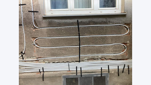 Detailansicht der befestigten Kunststoffrohre in der Wand, die nachfolgend mit Mörtel verputzt und mit einem Wärmedämmverbundsystem überdeckt werden.