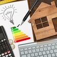 Energy efficiency rating graph on a desk with a wooden house model, calculator, folding ruler, light bulb and a computer keyboard