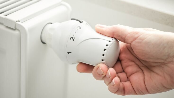 hand adjusting the temperature of heating radiator