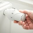 hand adjusting the temperature of heating radiator