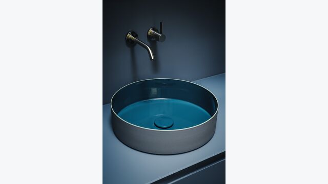 Ein Zusammenspiel von Form und Farbe im Waschbereich: Der Waschtisch Tri-Color aus Vitreon Stahl, die Kartell Laufen Armatur und das Arun Möbel.