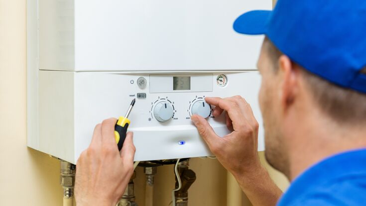 worker set up central gas heating boiler at home
