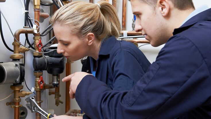 Female Trainee Plumber Working On Central Heating Boiler